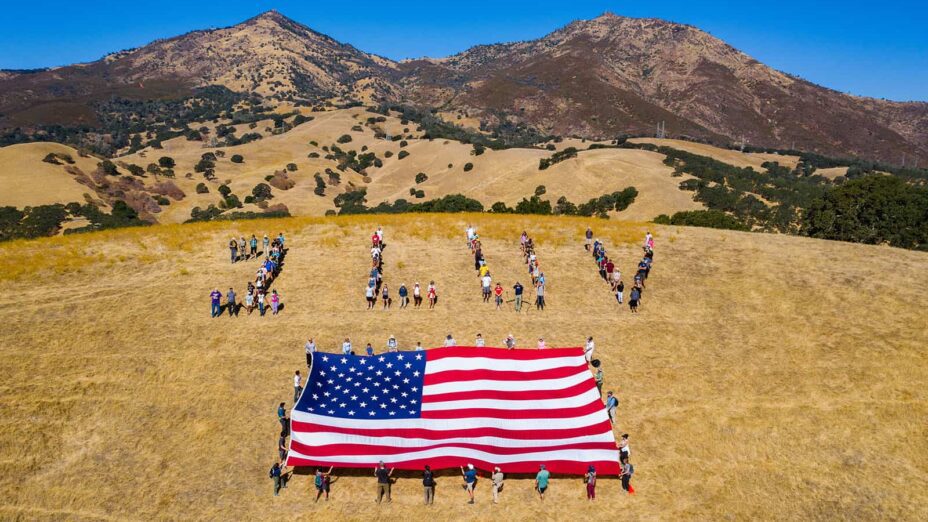 human banner spelling out 1 LUV with American flag