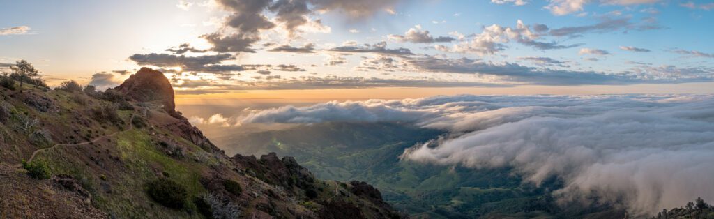 The Devil's Pulpit on Mount Diablo flanked by clouds and a setting sun below.