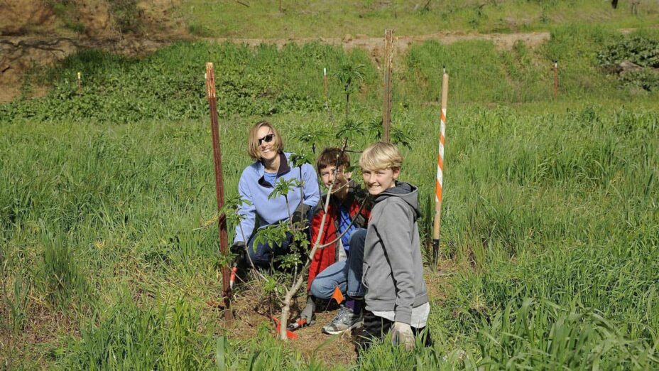 Mom and kids removing invasive weeds at a DiRT day