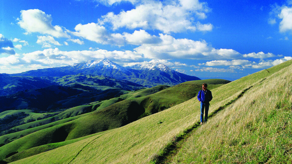 Man standing on trail overlooking hills