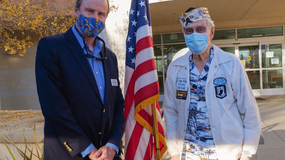 Ted Clement and Earl "Chuck" Kohler standing in front of an American flag