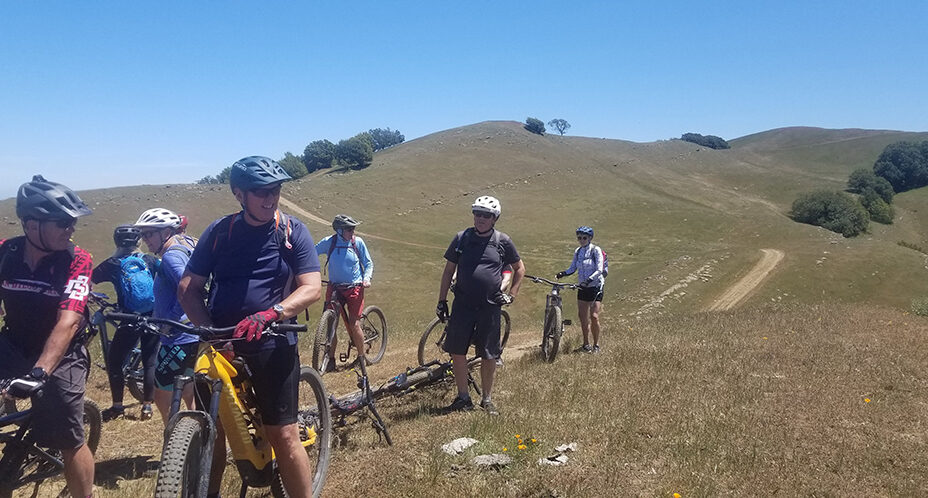 several cyclists on a fire road, surrounded by the hills