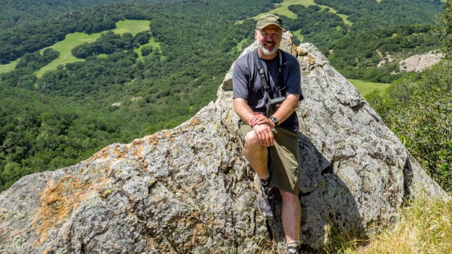 scott sitting on a rock with a green valley in the background