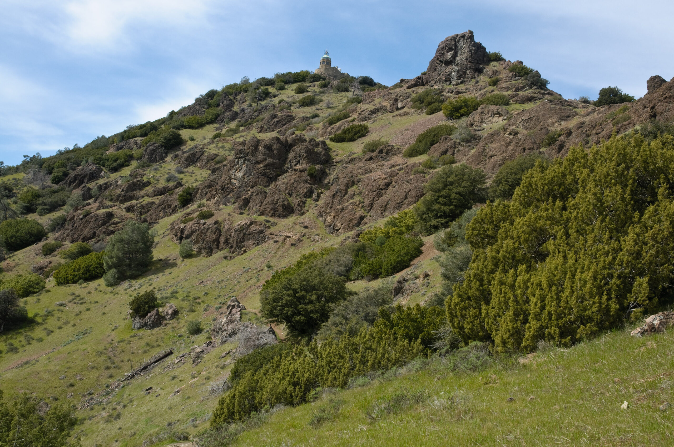 The Mount Diablo Summit Museum and Devils' Pulpit from the Devil's Elbow Trail cover in verdant green foliage. Photo by Scott Hein.