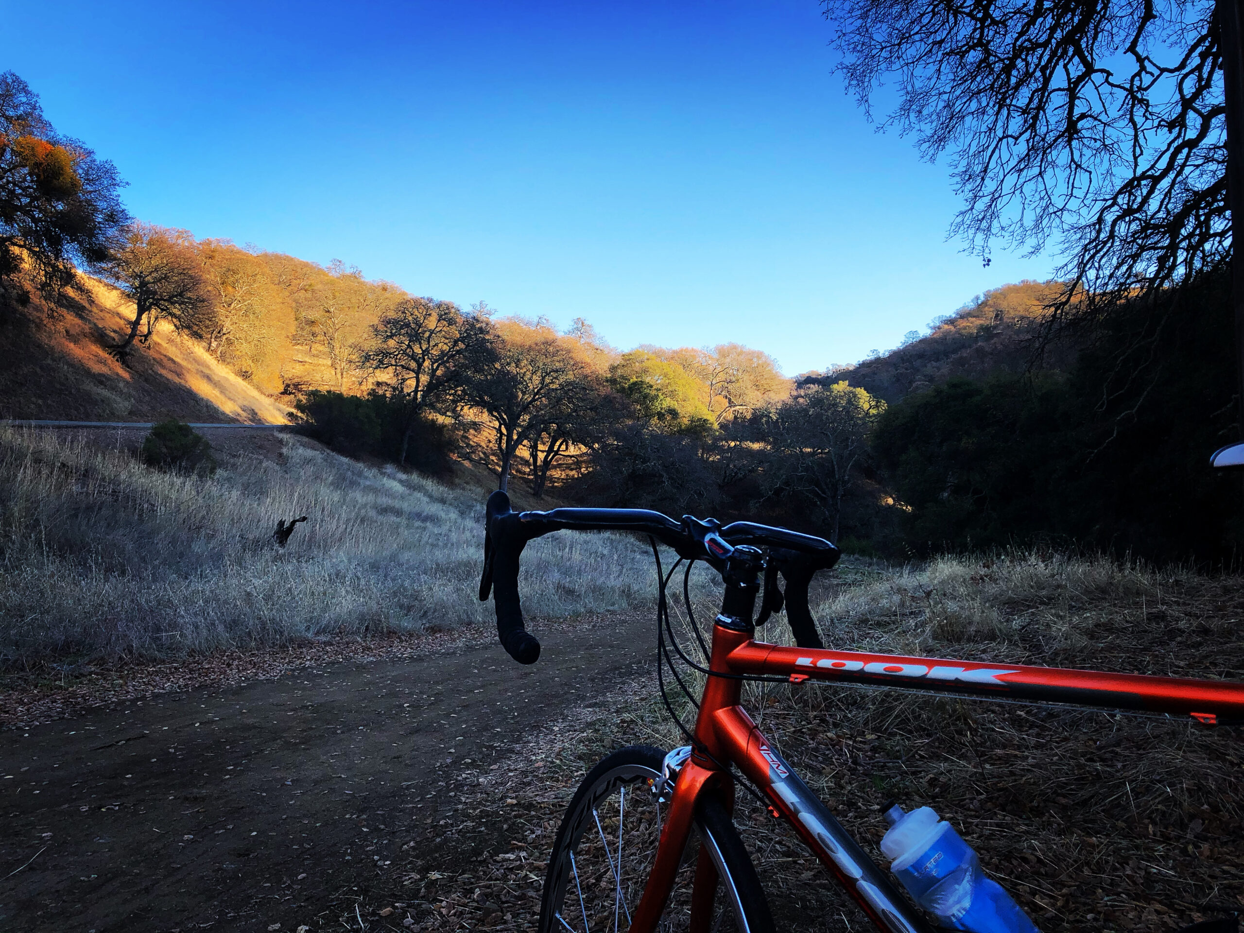 a vignetted image of a road bike amongst hills during golden hour.