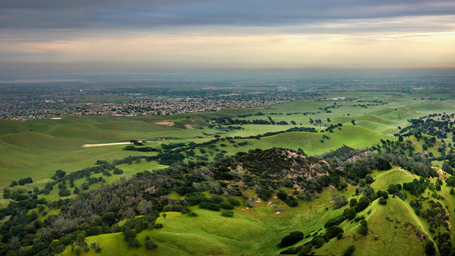 green hills of Sand Creek area with housing developments in the background